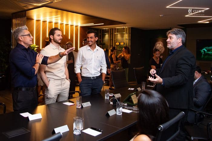 Membros reunidos à mesa em uma reunião do Club M